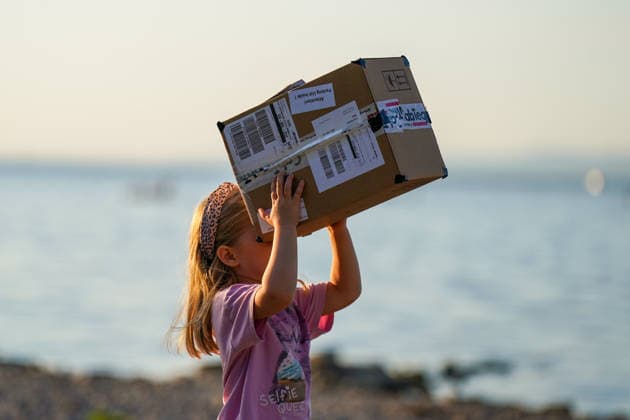 Altenrhein, Lake Constance, Switzerland: A girl observes a solar eclipse using a homemade pinhole camera made from a cardboard box. The child points the improvised projection device toward the sun; Lake Constance is visible in the background. Solar eclipse, partial solar eclipse, Sofi, astronomy, sun, pin Copyright: xJOERANxSTEINSIEKx