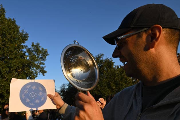 Hundreds Gather At Krakow s Historic Krakus Mound To Watch Solar Eclipse KRAKOW, POLAND - AUGUST 12: A man uses a kitchen colander as a makeshift pinhole projector to cast patterns of the solar eclipse onto a sheet of paper to watch a solar eclipse on August 12, 2026 in Krakow, Poland. Hundreds of residents and tourists ascended the historic prehistoric mound, which offers panoramic views of the city, equipped with protective eyewear and telescopes to witness the rare celestial event. Krakow Poland  Copyright: xArturxWidakx originalFilename: widak-hundreds260812_npvLC.jpg