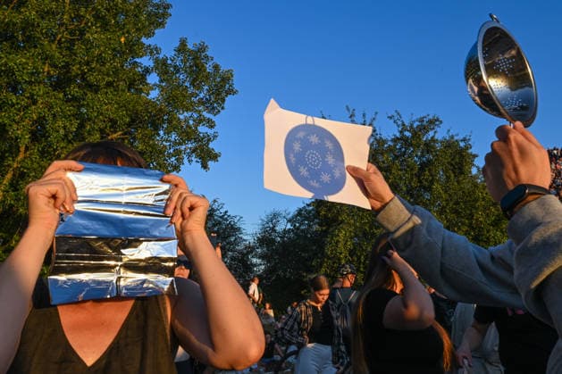 Hundreds Gather At Krakow s Historic Krakus Mound To Watch Solar Eclipse KRAKOW, POLAND - AUGUST 12: Onlookers use creative and improvised methods like aluminum foil, a kitchen colander, and a pinhole projector paper sheet to watch a solar eclipse in Krakow, Poland, on August 12, 2026. Hundreds of residents and tourists gathered on the slopes of the historic Krakus Mound (Kopiec Krakusa) during the late afternoon, utilizing both professional gear and DIY safety techniques to view the rare astronomical alignment. Krakow Poland  Copyright: xArturxWidakx originalFilename: widak-hundreds260812_npjeo.jpg