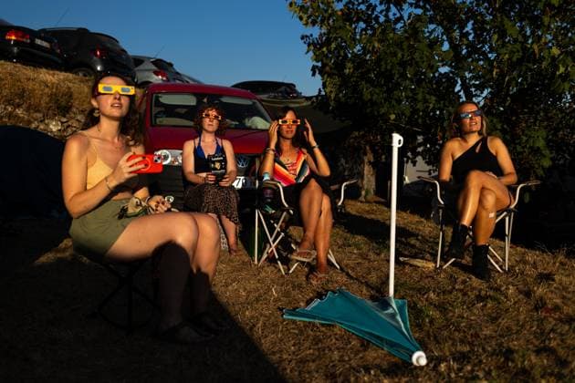 August 12, 2026, Paredes De Coura, Braga, Portugal: A group of festivalgoers wearing certified eclipse glasses sit on the festival grounds and watch the partial solar eclipse during the opening day of Vodafone Paredes de Coura. Paredes De Coura Portugal - ZUMAs197 20260812_aaa_s197_595 Copyright: xDiogoxBaptistax
