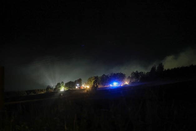 Marsberg, North Rhine-Westphalia, Germany, Europe: Wide-angle shot of a nighttime firefighting operation near the Diemel Dam. Thick plumes of smoke drift over the forested area while fire trucks with blue lights and work lights battle a forest fire. The shot shows the extent of the smoke and the ongoing firefighting efforts from a distance. Copyright: xAymanxAlahmedx