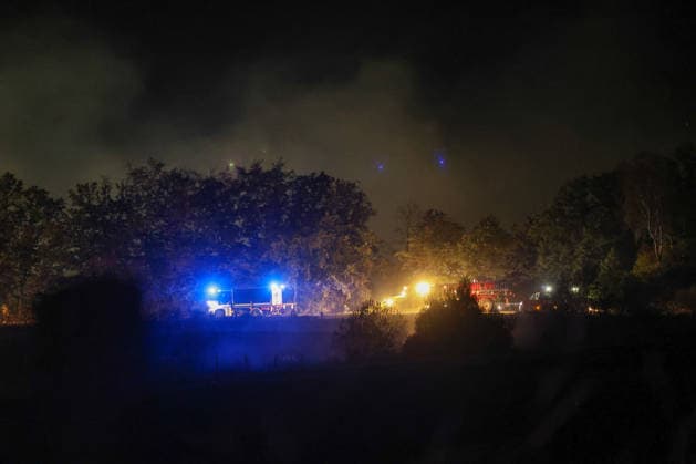 Marsberg, North Rhine-Westphalia, Germany, Europe Fire trucks and heavy-duty clearing equipment are in action during a nighttime forest fire operation near the Diemel Dam. Thick plumes of smoke rise above the forest, while blue lights and work lights illuminate the ongoing firefighting efforts and safety measures at the scene. Copyright: xAymanxAlahmedx