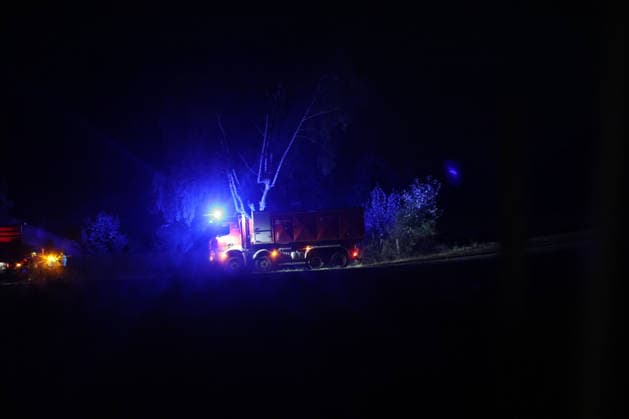 Marsberg, North Rhine-Westphalia, Germany, Europe: A fire truck stands by at the edge of the forest during a nighttime forest fire operation near the Diemel Dam. Blue lights illuminate the scene, while additional firefighters and vehicles continue to battle the blaze in the background. The photograph documents the ongoing firefighting operation at night. Copyright: xAymanxAlahmedx