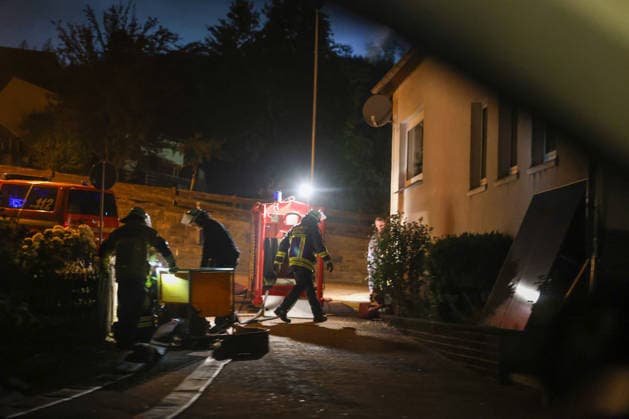 Helminghausen, Marsberg, North Rhine-Westphalia, Germany, Europe: Firefighters are preparing their equipment on a residential street during a nighttime forest fire operation near the Diemel Dam. Emergency vehicles, lighting, and hoses are set up in front of a residential building while firefighting efforts are being coordinated. Copyright: xAymanxAlahmedx