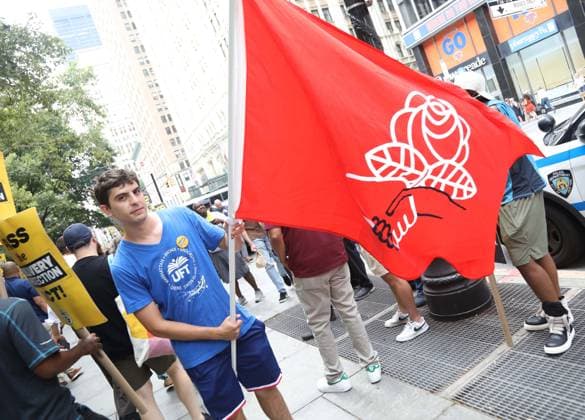 August 13, 2026, New York, New York, USA: A man with a Democratic Socialist of American (DSA) flag joins the Amazon Teamsters and Allies picket outside of City Hall for passage of the Delivery Protection Act. The Delivery Protection Act would require companies like Amazon to hire its workforce directly, essentially making Amazons corrupt third-party Delivery Service Partner model illegal in New York City. New York USA - ZUMAk03_ 20260813_zaf_k03_069 Copyright: xNancyxKaszermanx