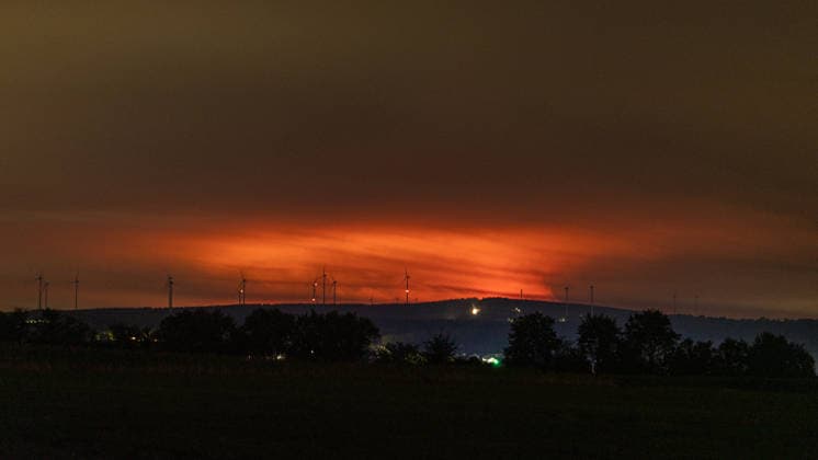 Nighttime photo of a forest fire in the High Fens behind wind turbines near Kleinhau. Nighttime photo taken from Kleinhau, in the municipality of Hürtgenwald. On the horizon, about 26 kilometers away in Belgium, a Copyright: xMarcxJohnx