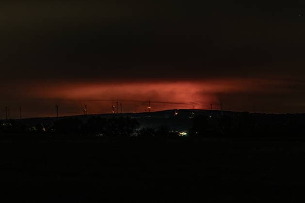 Night shot of a forest fire in the High Fens behind wind turbines near Kleinhau. Night shot taken from Kleinhau, in the municipality of Hürtgenwald. On the horizon, about 26 kilometers away in Belgium, a reddish g Copyright: xMarcxJohnx