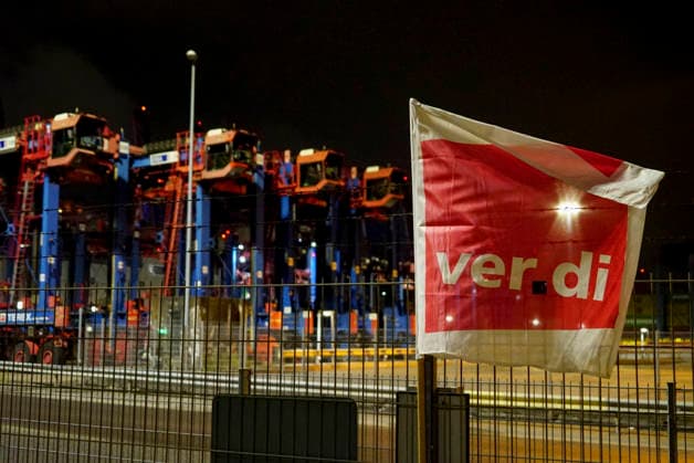 CNTV VERDI Everything is ready. Red and white VERDI flags are hanging at the Burchardkai Container Terminal in the Port of Hamburg for the warning strike by port workers and employees. On the night of August 17, 2026, in the Port of Hamburg. Slogan: 24-hour, 3-shift warning strike during collective bargaining for seaports—VERDI calls for a w