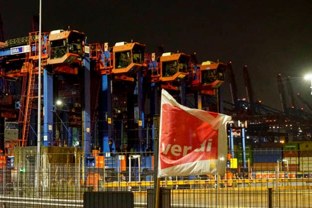 CNTV VERDI Everything is ready. Red and white VERDI flags are hanging at the Burchardkai Container Terminal in the Port of Hamburg for the warning strike by port workers and employees. On the night of August 17, 2026, in the Port of Hamburg. Slogan: 24-hour, 3-shift warning strike. Collective bargaining round for seaports. VERDI calls for a