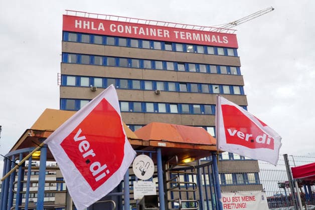 CNTV VERDI Striking workers with red-and-white VERDI flags at the Port of Hamburg; Port of Hamburg at Burchardkai; HHLA Container Terminal; warning strike by port workers on August 18, 2026, at the Port of Hamburg; slogan: 24 hours, 3 shifts ; warning strike during collective bargaining negotiations for maritime workersVer.di calls for a 24-hour warning strike