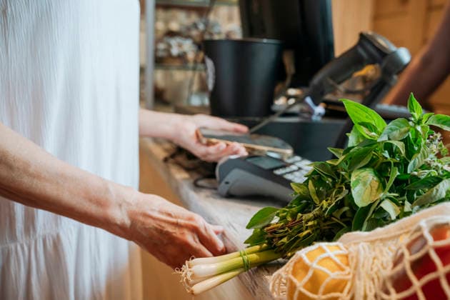 Mature woman paying for fresh produce with smartphone at checkout, OSF02924