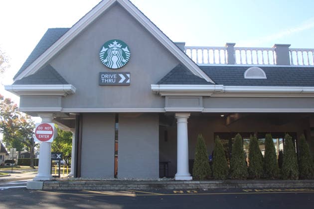 October 12, 2024, New York, New York, USA: Exterior of a Starbucks coffee shop with drive-thru service in a suburban shopping area in the United States. The image shows the front entrance, drive-thru directional signage, columns, and trimmed shrubs outside the caf e building during daytime. New York USA  - ZUMAle1_ 20241012_faf_le1_004 Copyright: xMitchellxLevyx