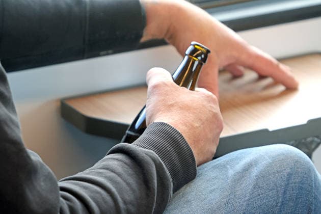 Alcohol Ban at Train Stations: A man is drinking a bottle of beer on an S-Bahn train, but is not allowed to carry an open bottle with him at train stations or on station forecourts