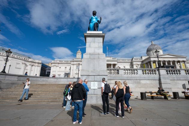 September 12, 2026, London, United Kingdom: People read the plaque at the base of the Fourth Plinth, currently showcasing the sculpture Lady in Blue, in Trafalgar Square, London. Lady in Blue, a bronze sculpture by New York-based artist Tschabalala Self, stands on the Fourth Plinth in Trafalgar Square, London. Unveiled on 10 September, the work pays homage to a young metropolitan woman of colour and was created as a contemporary everywoman representing the diversity of London today. The sculpture explores themes of representation, recognition and equity, presenting an everyday woman walking forward into a shared future rather than a traditional historical figure or monument. The bronze sculpture is patinated in Lapis Lazuli blue, a pi - ZUMAs197 20260912_aaa_s197_272 Copyright: xAndreaxDomeniconix