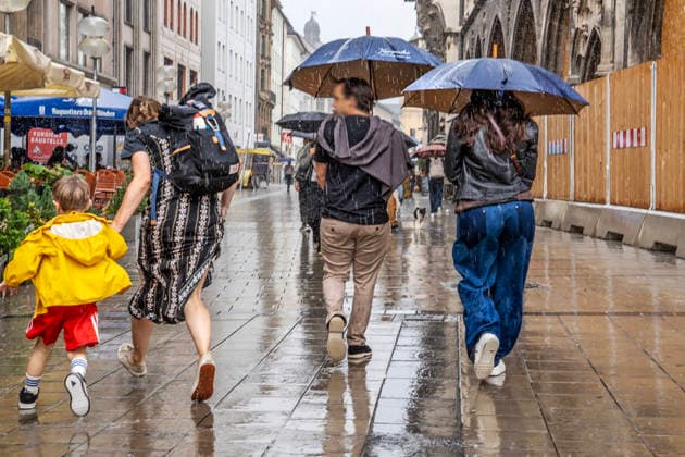 A woman flees with her child from the heavy rain, while other passersby hurry toward Theatinerstraße with umbrellas; heavy rain on Wednesday afternoon, Munich, September 16, 2026, Germany, Munich, September 2026, a