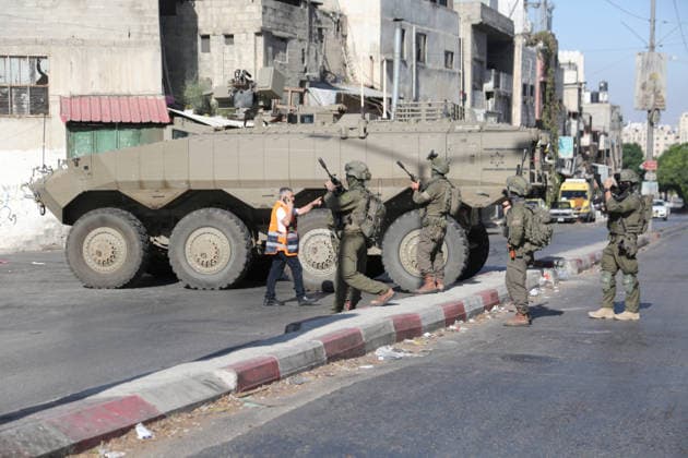 September 17, 2026, Nablus, Palestine: A Palestinian paramedic argues with Israeli soldiers near armored Israeli military vehicles blocking the main road at the entrance to the Ein refugee camp, west of Nablus in the West Bank, during an Israeli military operation to search for weapons. Residents reported that the army raided and searched homes and arrested five people, and some people were injured after being severely beaten. Nablus Palestine  - ZUMAs197 20260917_aaa_s197_064 Copyright: xNasserxishatyehx