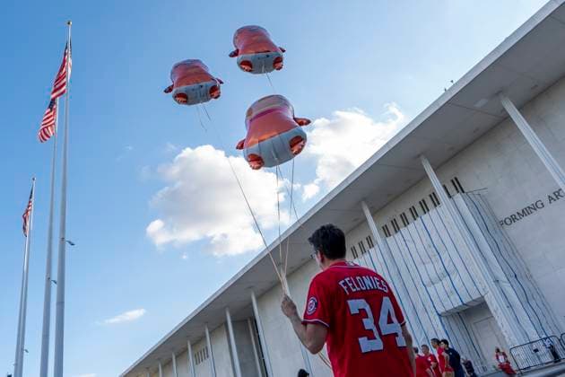 September 18, 2026, Washington, Dc, USA: A man holds balloon effigies of Donald Trump outside the Kennedy Center ahead of the Hands Around the Kennedy Center demonstration..Supporters of the Kennedy Center gathered for the protest in response to this week s escalating tensions over the arts institution s future, including the Trump-appointed board voting to close the center in defiance of a court order, testimony that contractors were ramming the pillars of the building with construction equipment, and photographs showing President Trump aboard Air Force One with a poster that read Kennedy Center DEMOLISHED Washington USA  - ZUMAs197 20260918_aaa_s197_063 Copyright: xJenxGolbeckx