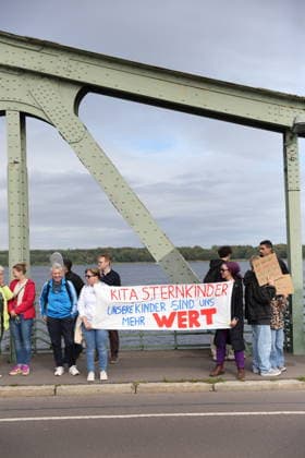 Protesters holding a banner reading Kita Sternkinder: Our Children Are Worth More to Us during a protest under the slogan Education Needs Democracy, Democracy Needs Education on the Glienicker Bridge between Berlin and Potsdam, September 19, 2026. Education Policy Protest on the Glienicker Bridge