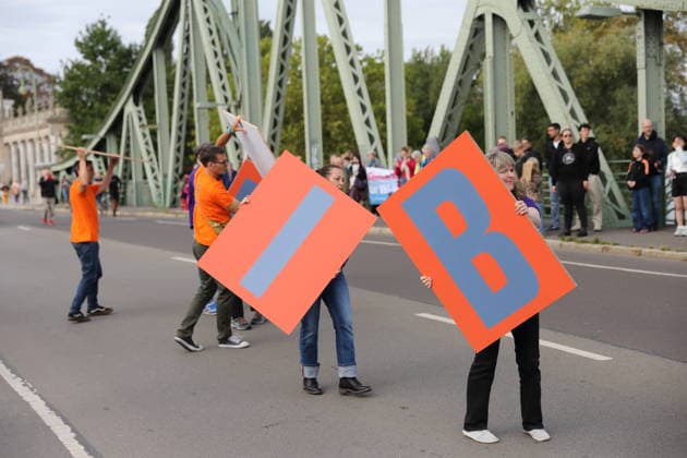 Protesters hold up signs that, when put together, spell out the words Education and Democracy during a protest under the slogan Education Needs Democracy, Democracy Needs Education on the Glienicker Bridge between Berlin and Potsdam, September 19, 2026. Education Policy Protest on the Glienicker Bridge
