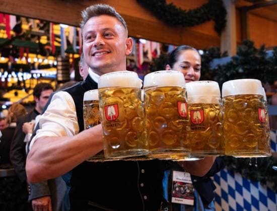 (260919) -- MUNICH, Sept. 19, 2026 -- A staff member carries cups of beer at the Oktoberfest in Munich, Germany, Sept. 19, 2026. The 191st Oktoberfest, one of the largest folk festivals in Germany, opened on Saturday in Munich, with mayor Dominik Krause tapping the first barrel of beer as a tradition. This year s festival will last until Oct. 4. ) GERMANY-MUNICH-OKTOBERFEST-OPENING ZhangxHaofu 