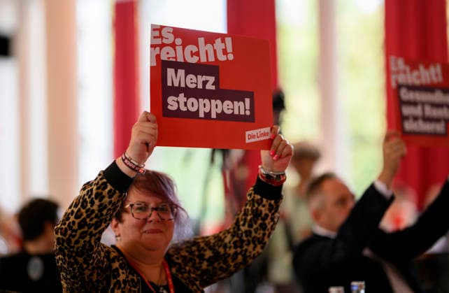 A delegate holds up a sign reading Stop Merz—Enough Is Enough on September 19, 2026, at the Left Party NRW State Convention, held on September 19, 2009, at the Stadthalle in Mülheim an der Ruhr, Germany.