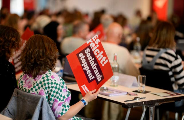 A delegate holds a sign reading Stop Social Plunder—Enough Is Enough at the Left Party NRW State Convention on September 19, 2026, held on September 19, 2009, at the Stadthalle in Mülheim an der Ruhr, Germany.