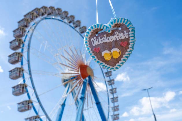 Gingerbread heart from Oktoberfest in front of the Ferris wheel against a blue sky, souvenir to mark the start of Oktoberfest, opening day, September 19, 2026, Germany, Munich, September 19, 2026, Oktoberfest 2026, Oktoberfest gingerbread heart in front of the Ferris wheel under a blue sky, souvenir, Wiesn kickoff in bright sunshine and te