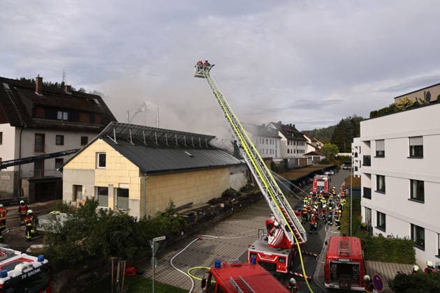 Firefighters are extinguishing the fire from the rear of the building at Am Posthaler using a turntable ladder; the fire is in the former workshop building of Naturstein Stefan Wormser, located on Pestalozzistraße and Friedhofsweg in Pegnitz, September 20, 2026, Upper Franconia, Bavaria,