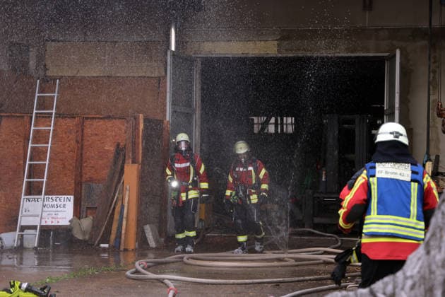 Two firefighters are running out of the building; there is a fire in the former Naturstein Stefan Wormser workshop building, located at Pestalozzistraße and Friedhofsweg, 20 09 2026, Upper Franconia, Bavaria,
