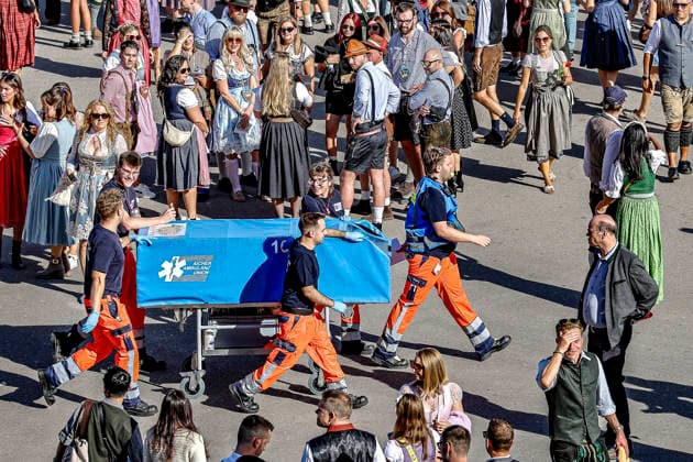 Tens of thousands of visitors celebrate Oktoberfest on the first day of the Wiesn in 2026 in Munich. Scenes from the Wiesn 2026. Not all visitors are able to leave the festival grounds on their own two feet in the afternoon. Paramedics wheel a patient on a covered stretcher toward an ambulance. Munich, Theresienwiese, Bavaria, Germany