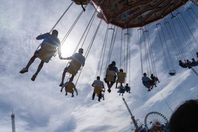 Oktoberfest visitors soar through the Munich sky on the Wellenflug chain carousel, Oktoberfest, Munich, September 20, 2026, Germany, Munich, September 20, 2026, Oktoberfest visitors soar through the Munich sky on the Wellenflug chain carousel, backlit by the sun, Sunday afternoon, Oktoberfest, typically Bavarian, the sky is slightly cloudy, weekend, folk fes