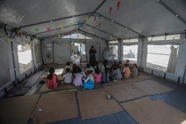 Gaza Temporary Tent Classrooms Palestinian children sit facing a teacher inside a temporary classroom tent in western Gaza City, Gaza Strip on September 20, 2026. Thousands of Palestinian children in the Gaza Strip have resumed lessons in temporary classrooms as the education system continues to face widespread disruption and damage following the war. Temporary learning spaces, including tents, are being used as schools and educational facilities remain damaged or unavailable. Gaza Gaza Strip Palestinian Territories Copyright: xFaizxQreqax