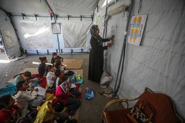 Gaza Temporary Tent Classrooms Palestinian children sit facing a teacher inside a temporary classroom tent in western Gaza City, Gaza Strip on September 20, 2026. Thousands of Palestinian children in the Gaza Strip have resumed lessons in temporary classrooms as the education system continues to face widespread disruption and damage following the war. Temporary learning spaces, including tents, are being used as schools and educational facilities remain damaged or unavailable. Gaza Gaza Strip Palestinian Territories Copyright: xFaizxQreqax