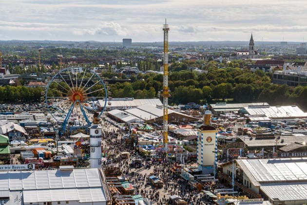 Oktoberfest 2026, panoramic view of the Wiesn featuring the Ferris wheel, the Hangover ride, and festival tents stretching all the way to Munich’s Sendling district, with sunshine and a temperature of 21 degr
