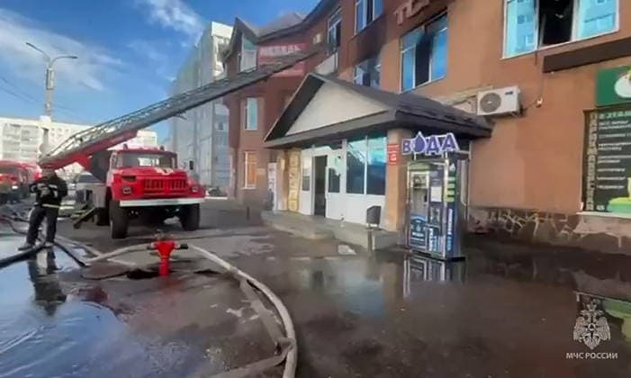 RUSSIA, STERLITAMAK - SEPTEMBER 22, 2026: Emergency workers deploy an aerial ladder platform to battle a fire at the Solnechny shopping centre. Video grab. Best possible quality. Ministry of Emergency Situations TASS  98135334