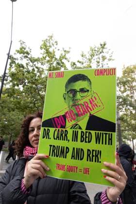 September 23, 2026, New York, New York, USA: A protester holds a sign that reads MT SINAI COMPLICIT DO NO HARM! DR. CARR, IN BED WITH TRUMP AND RFK TRANS EQUITY equals LIFE with an image of Dr. Carr. ACT UP NY leads a coalition of organizations blockading the entrance to 1 WTC and later blocking traffic on the West Side Highway demonstrating under the banner AI OUT OF OUR HEALTHCARE! PALANTIR OUT OF MOUNT SINAI! as the Newsweek AI Health Summit is held inside the building and a keynote speaker is Dr. Brendan Carr, (not pictured) CEO of Mount Sinai. Approximately 20 protesters are arrested by NYPD. Part of the MONEY FOR AIDS and HEALTHCARE! NOT FOR ICE and WARFARE! ACT UP (AIDS Coalition To Unleash Power) campaign, demonstrators denounce  - ZUMAr174 20260923_znp_r174_007 Copyright: xGinaxMxRandazzox