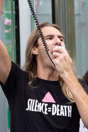 September 23, 2026, New York, New York, USA: A speaker wears a shirt that reads SILENCE equals DEATH. ACT UP NY leads a coalition of organizations blockading the entrance to 1 WTC and later blocking traffic on the West Side Highway demonstrating under the banner AI OUT OF OUR HEALTHCARE! PALANTIR OUT OF MOUNT SINAI! as the Newsweek AI Health Summit is held inside the building and a keynote speaker is Dr. Brendan Carr, (not pictured) CEO of Mount Sinai. Approximately 20 protesters are arrested by NYPD. Part of the MONEY FOR AIDS and HEALTHCARE! NOT FOR ICE and WARFARE! ACT UP (AIDS Coalition To Unleash Power) campaign, demonstrators denounce Mount Sinai s contract with Palantir, a surveillance, data analytics and military tech company. P  - ZUMAr174 20260923_znp_r174_005 Copyright: xGinaxMxRandazzox