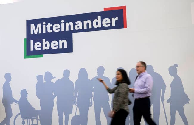 Feature, Slogan: Living Together with the Shadows of Different People ; in the foreground, visitors to REHACARE, the trade fair for rehabilitation and care, September 23–26, 2026, in Düsseldorf, Germany