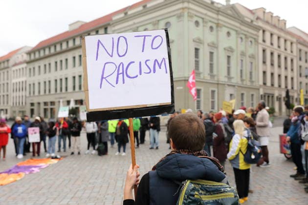 A protester stands outside the state parliament holding a sign that reads No to racism during a demonstration against the prepaid card for refugees in Brandenburg, Potsdam, September 25, 2026. Demonstration against the prepaid card in Potsdam
