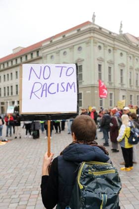 A protester stands outside the state parliament holding a sign that reads No to racism during a demonstration against the prepaid card for refugees in Brandenburg, Potsdam, September 25, 2026. Demonstration against the prepaid card in Potsdam