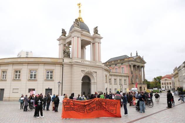 Protesters holding banners reading No one is illegal, Personne n’est clandestine, Kein Mensch ist illegal, Hicbir insan illegal degildir, and Ninguna persona es illegal stand outside the state parliament during a demonstration against the prepaid card for refugees in Brandenburg, Potsdam, September 25, 2026. Demonstration against the prepaid card in Potsdam