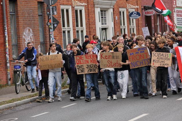Protesters march with signs reading No to the Military Recruitment Center, The Rich Want War, the Youth Want a Future, No Advertising for Death, School Won’t Help You on the Front Lines, and Increase Social Spending, Cut Military Spending down Kurfürstenstraße during a demonstration against the draft, Potsdam, September 25, 2026 School strike against the draft in Pot