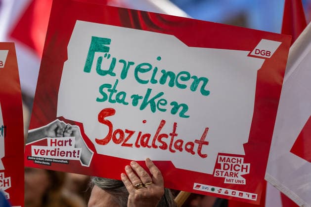 DGB Bavaria: Hard-Earned Large Rally, Nuremberg, September 26, 2026 A participant at a DGB Bavaria rally holds aloft a sign reading For a Strong Welfare State. Her gesture appears resolute; in the background, additional posters bearing the slogan Hard-Earned can be seen. Nuremberg, Bavaria, Germany 20260926-1V9A9705-M4000