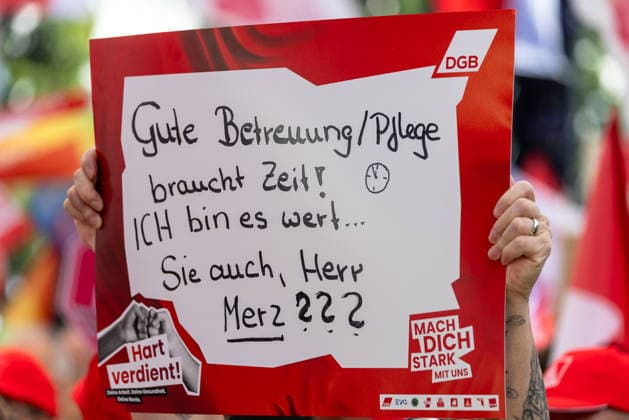 DGB Bavaria Hard-Earned Large Rally, Nuremberg, September 26, 2026 A participant at a DGB rally holds a handwritten sign with the demand Good Care Takes Time—I’m Worth It, and So Are You, Mr. Merz. The sign also bears the slogan Hard-Earned, as well as the DGB logo and the call to action Stand up with us. Nuremberg, Bavaria, Germa 20260926-1V9A9795-M4000