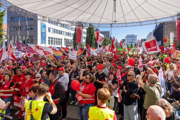 DGB Bavaria Hard-Earned Large Rally, Nuremberg, September 26, 2026 Numerous participants gather at the Kornmarkt for a rally organized by DGB Bavaria under the slogan Hard-Earned. The crowd waves flags of ver.di and other unions; several people are wearing red safety vests and shirts, while others applaud with their hands raised. Nuremberg, 20260926-286A9235-M4000