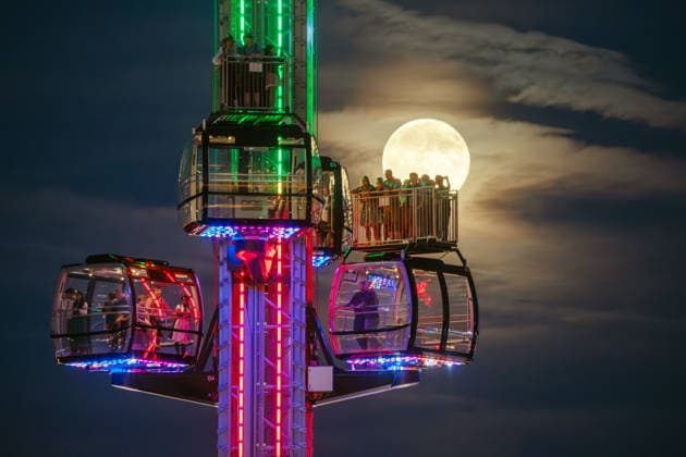 The full moon, also known as the Harvest Moon, shines behind the SkyLift at Oktoberfest; festivalgoers in the gondolas and on the open grounds take photos with their smartphones, Munich, September 26, 2026, Germany, Munich, September 26, 2026—the full moo