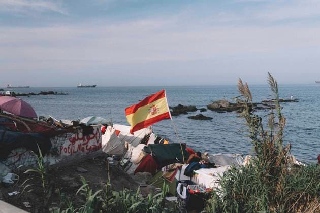 September 26, 2026, Ceuta, Ceuta, Spain: A Spanish flag flies over makeshift shelters built by migrants on the rocky shore of Ceuta. Thousands of migrants, most of them young Moroccan men, have been living in makeshift settlements in the Spanish North African enclave of Ceuta since a mass arrival at the end of July 2026 set off a migration and political crisis. Ceuta Spain - ZUMAs392 20260926_zip_s392_004 Copyright: xFabianxSuspensivox