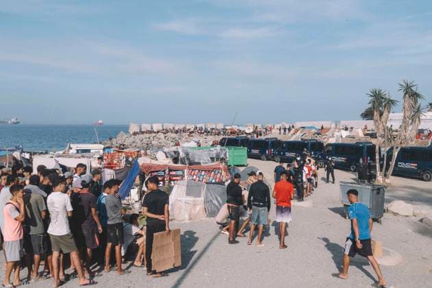 September 26, 2026, Ceuta, Ceuta, Spain: Migrants queue next to Spanish National Police vans on the seafront of Ceuta. Thousands of migrants, most of them young Moroccan men, have been living in makeshift settlements in the Spanish North African enclave of Ceuta since a mass arrival at the end of July 2026 set off a migration and political crisis. Ceuta Spain - ZUMAs392 20260926_zip_s392_007 Copyright: xFabianxSuspensivox