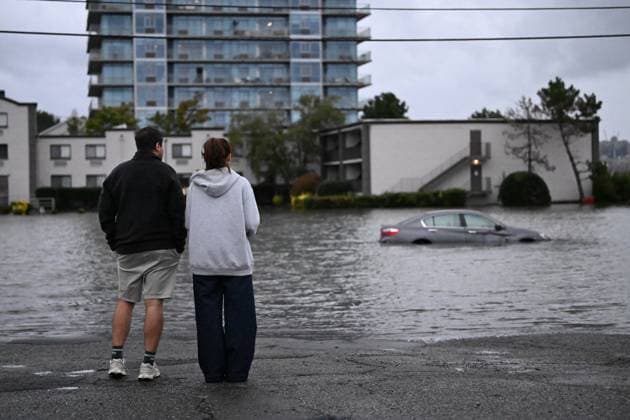 September 26, 2026, Edgewater, New Jersey, USA: Two people watch in shock as a vehicle is submerged in flood waters in the parking lot of the Comfort Inn Edgewater on Hudson River during a nor easter storm in Edgewater, New Jersey, United States on Saturday, Sept. 26, 2026. Heavy rain and strong winds battered the northeastern United States as an unusually powerful autumn storm intensified, forcing the cancelation of hundreds of flights and leaving tens of thousands of people without power. New York, Boston and Philadelphia were all in the crosshairs of the Nor easter -- so labeled for its northeasterly winds -- as authorities warned of potential major flooding and road closures. Edgewater USA - ZUMAs197 20260926_aaa_s197_289 Copyright: xKylexMazzax