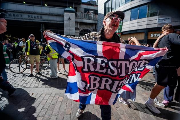 September 26, 2026, London, United Kingdom: A Restore Britain supporter holds up a Union Jack in front of New Scotland Yard during a protest against grooming gangs targeting British girls. The event organised by Together For The Children in collaboration with Football Lads on National Survivors Day stands in solidarity with survivors of child sexual abuse and sexual violence while demanding stronger child protections and legal reforms, as well as a curb on illegal migration. London United Kingdom - ZUMAs197 20260926_aaa_s197_318 Copyright: xLabxMox